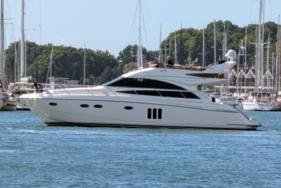 Luxury 2009 Princess 54 yacht cruising in a marina with sailboats in the background.