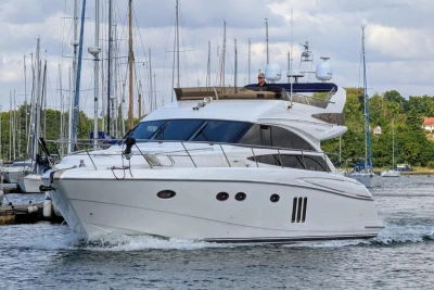 Luxury 2009 Princess 54 yacht cruising in a marina with sailboats in the background.
