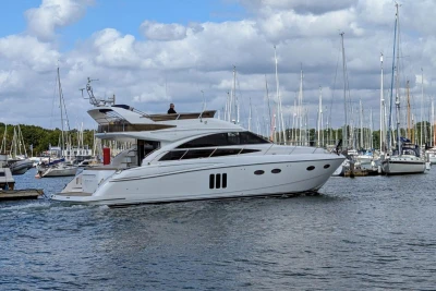 Luxury 2009 Princess 54 yacht cruising in a marina with sailboats in the background.