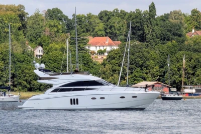 Luxurious 2009 Princess 54 yacht cruising on a serene river, surrounded by lush greenery.