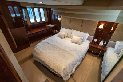 Luxurious bedroom interior of 2009 Princess 54 yacht with elegant bedding and wood accents.