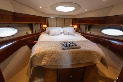 Luxurious cabin interior of 2009 Princess 54 yacht with elegant bedding and porthole windows.