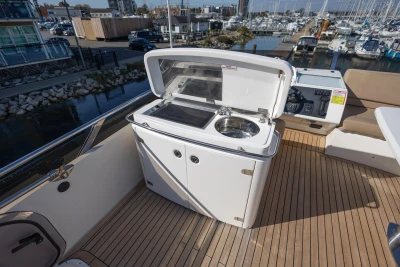 Outdoor kitchenette on 2009 Princess 54 yacht with sink and grill, docked at marina.