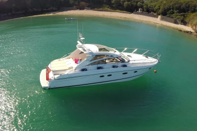 2006 Princess V48 yacht anchored in clear turquoise waters near a sandy beach.