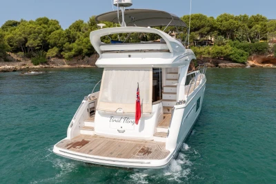 2018 Princess 49 yacht on serene water, surrounded by lush greenery.