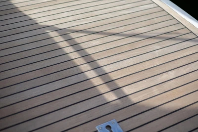 Teak deck of 2005 Princess 42 Flybridge Motor Yacht with shadow and metal fixture.