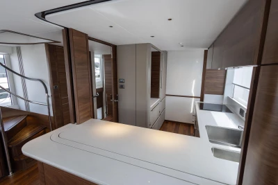 Modern kitchen interior on 2023 Princess X80 yacht, featuring sleek countertops and wooden cabinetry.