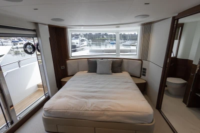 Luxurious bedroom interior of 2023 Princess X80 yacht with marina view.