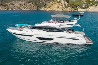 Luxurious 2018 Princess S65 yacht cruising in clear blue waters near rocky coastline.
