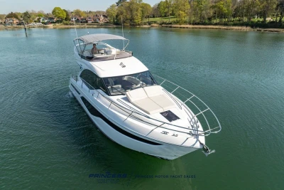 2025 Princess F50 yacht cruising on a serene lake with lush greenery.