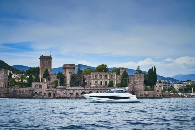 2026 Princess V50 Open yacht cruising near historic castle on a serene waterway.