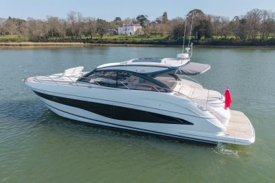 2026 Princess V50 Open yacht cruising on a serene river with lush greenery.