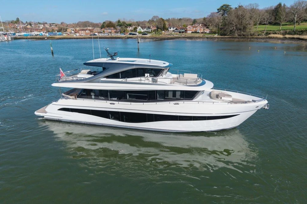 Luxurious 2026 Princess X80 yacht cruising on serene waters near a picturesque shoreline.
