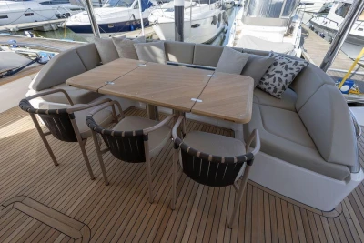 Luxurious seating area on 2026 Princess X80 yacht with wooden table and cushioned chairs.