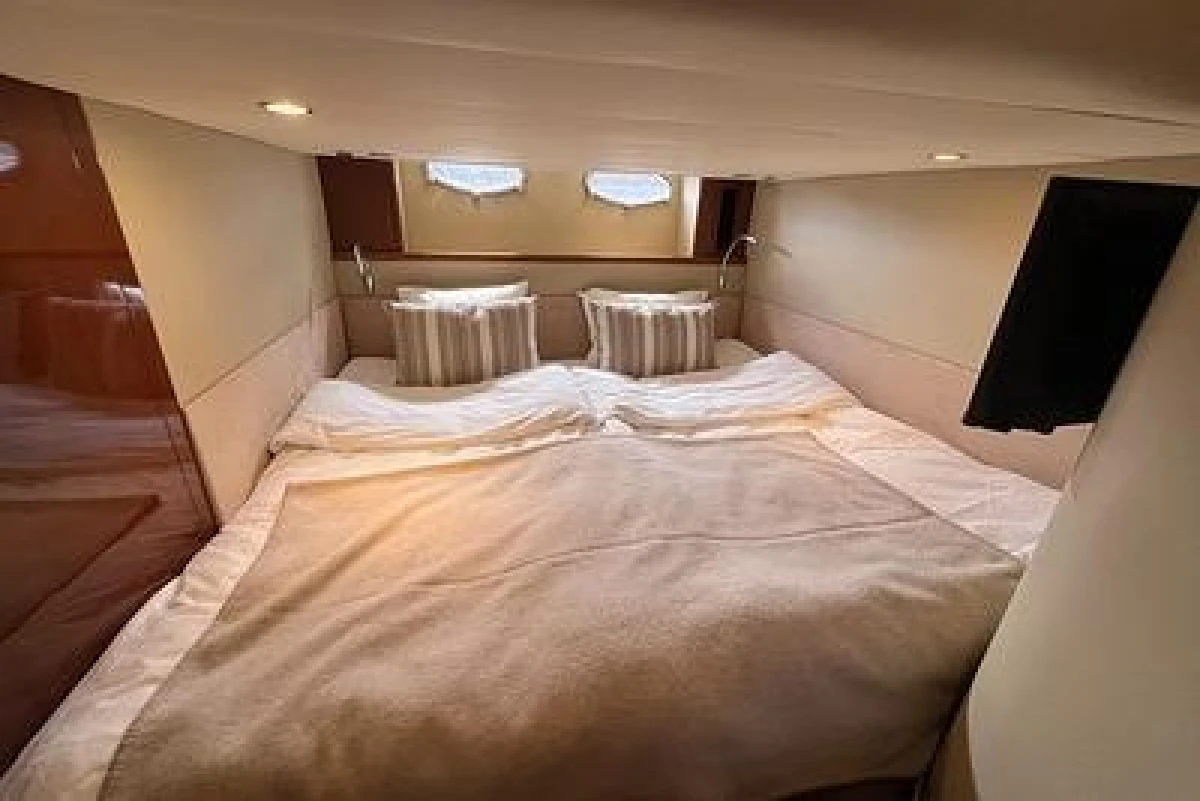 Luxurious cabin interior of 2007 Princess V48 yacht with cozy bedding and ambient lighting.