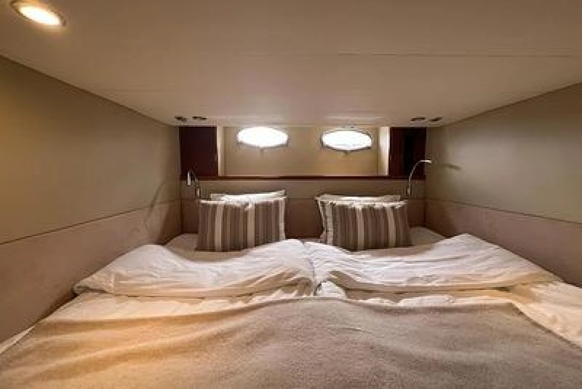 Cozy cabin interior of 2007 Princess V48 yacht with twin beds and striped pillows.