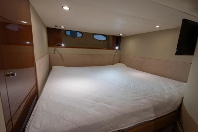 Luxurious cabin interior of 2007 Princess V48 yacht with cozy bedding and ambient lighting.