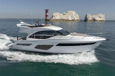 Luxury Princess F50 yacht cruising near rocky coastline, 2022 model.
