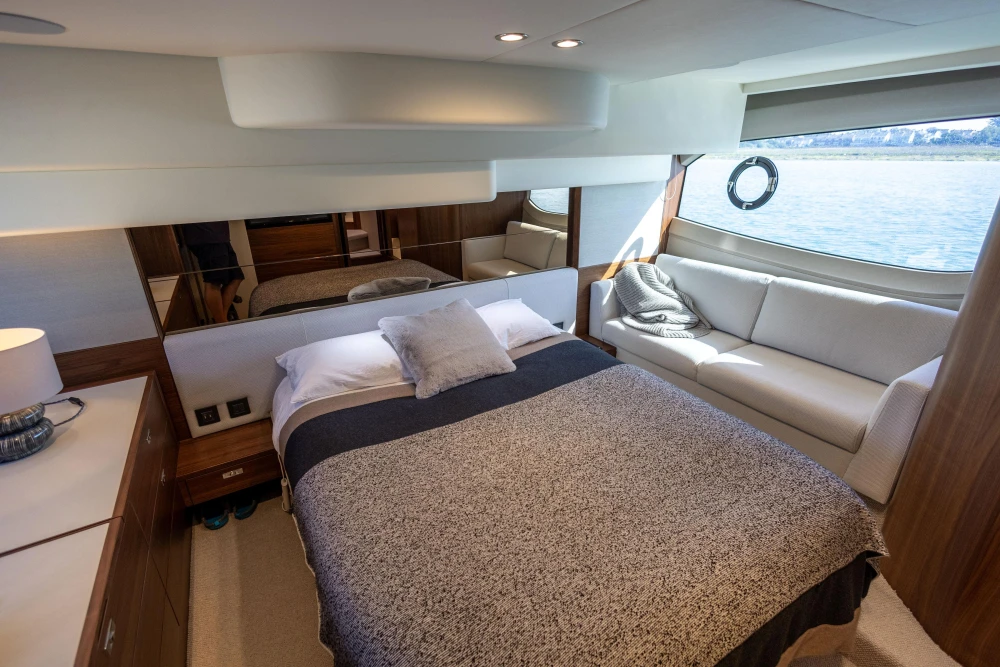 Luxurious 2022 Princess F50 yacht bedroom with bed, sofa, and ocean view.