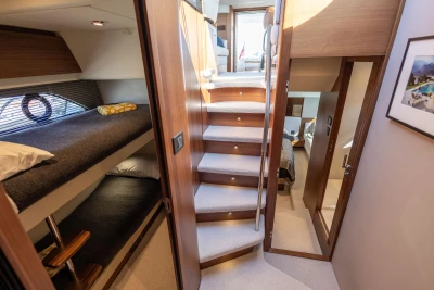 Interior of 2022 Princess F50 yacht with bunk beds and wooden staircase.