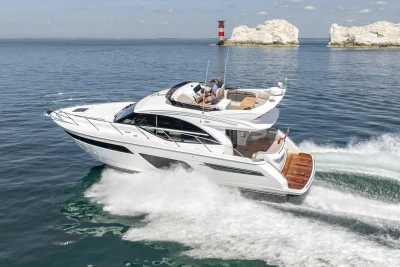 Luxury 2022 Princess F50 yacht cruising on open water near rocky coastline.