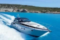 2005 Princess V58 yacht cruising in clear blue waters near rocky coastline.