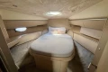 Luxurious cabin interior of 2005 Princess V58 yacht with cozy bed and elegant wood finish.