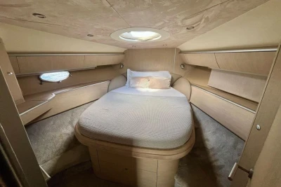 Luxurious cabin interior of 2005 Princess V58 yacht with cozy bed and elegant wood finish.