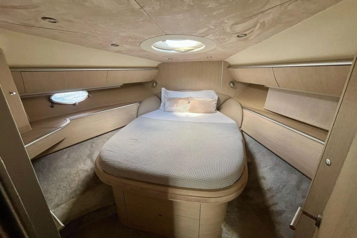 Luxurious cabin interior of 2005 Princess V58 yacht with cozy bed and elegant wood finish.