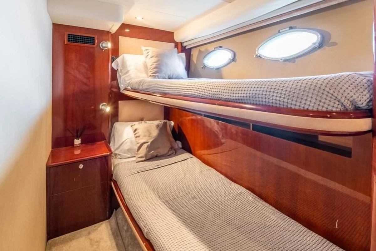 Interior of 2005 Princess V58 yacht with cozy twin bunk beds and wooden cabinetry.