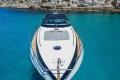 2005 Princess V58 yacht on clear turquoise water near rocky shoreline.