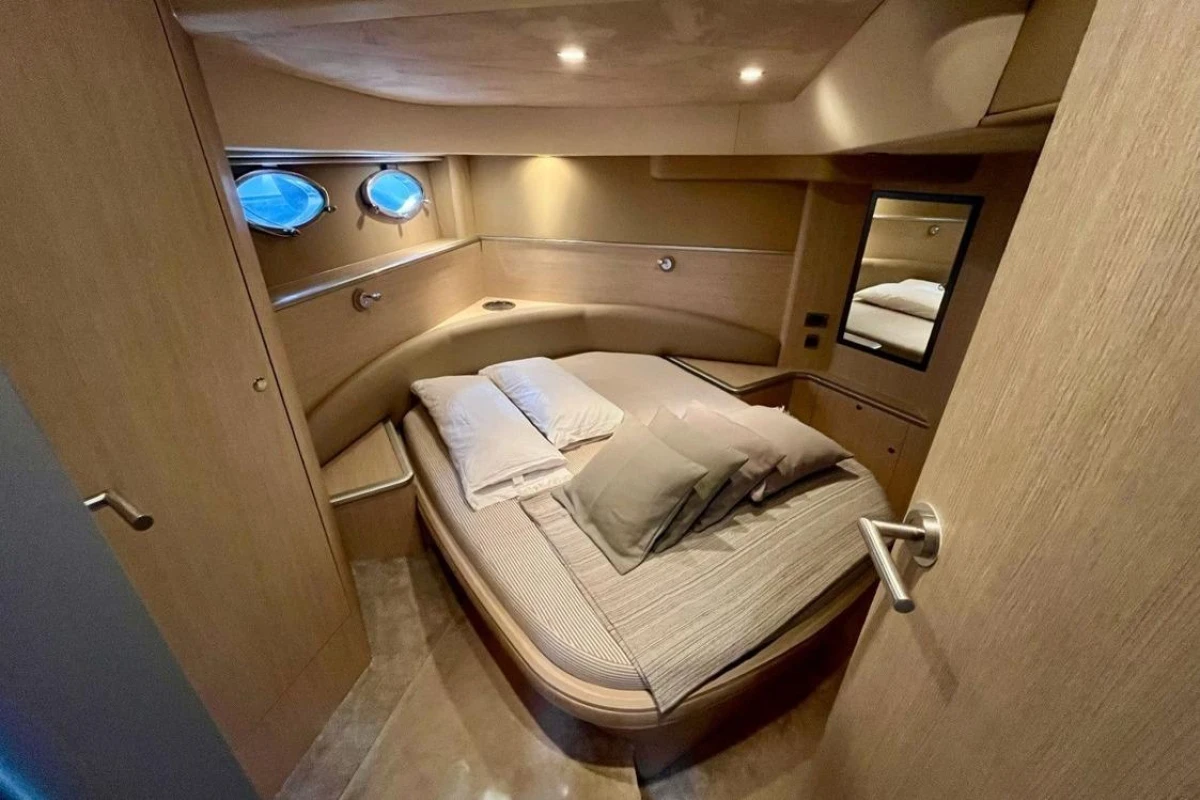 Luxurious cabin interior of 2005 Princess V58 yacht with cozy bed and porthole windows.