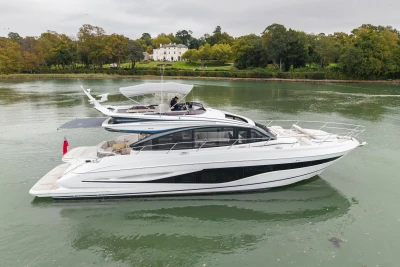 2025 Princess S65 yacht on serene river with lush green backdrop.