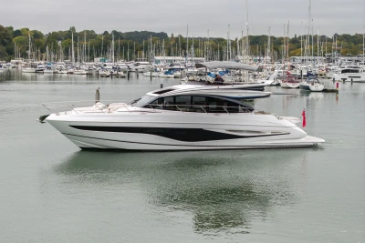 2025 Princess S65 yacht cruising in a marina with numerous sailboats.