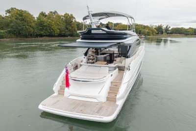 Luxury 2025 Princess S65 yacht cruising on a serene river with lush greenery.